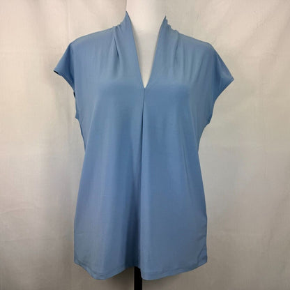 A light blue short-sleeve blouse with a split V-neckline, displayed on a mannequin torso against a light gray fabric backdrop.
