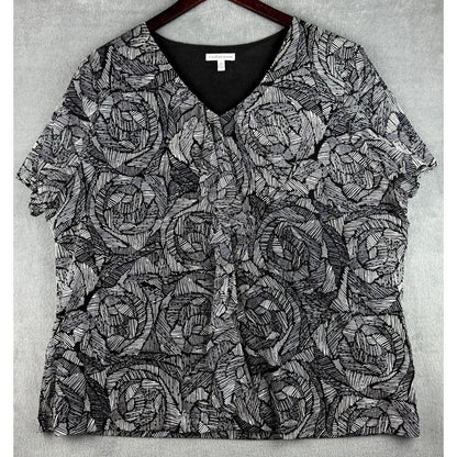 A short-sleeve V-neck blouse with an all-over black and gray abstract line pattern, hanging on a dark wooden hanger against a textured gray background.
