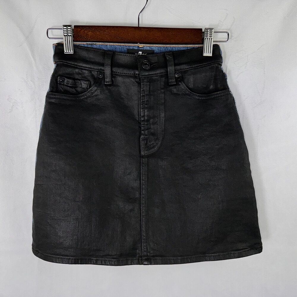 A black washed denim mini skirt with a front button closure and belt loops, hanging on a wooden hanger against a white textured background.