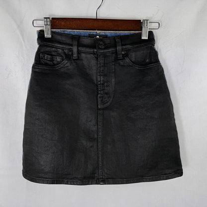 A black washed denim mini skirt with a front button closure and belt loops, hanging on a wooden hanger against a white textured background.