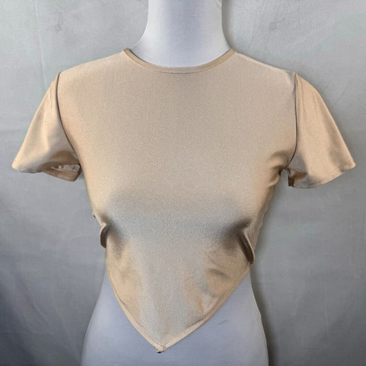 A beige short-sleeve crop top with a draped, asymmetrical hem, displayed on a white mannequin torso against a gray fabric backdrop.