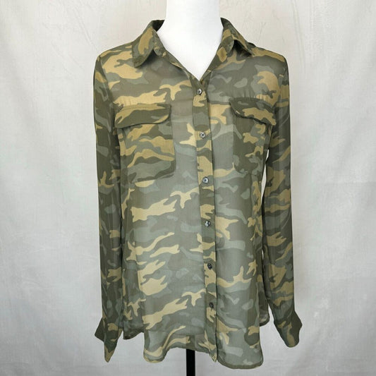 A long-sleeve button-up shirt with a green and tan camouflage pattern, displayed on a white mannequin torso against a light gray fabric backdrop.