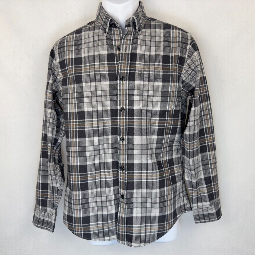 A long-sleeve button-down plaid shirt in black, gray, and white with thin tan stripes, displayed on a white mannequin torso against a light off-white background.
