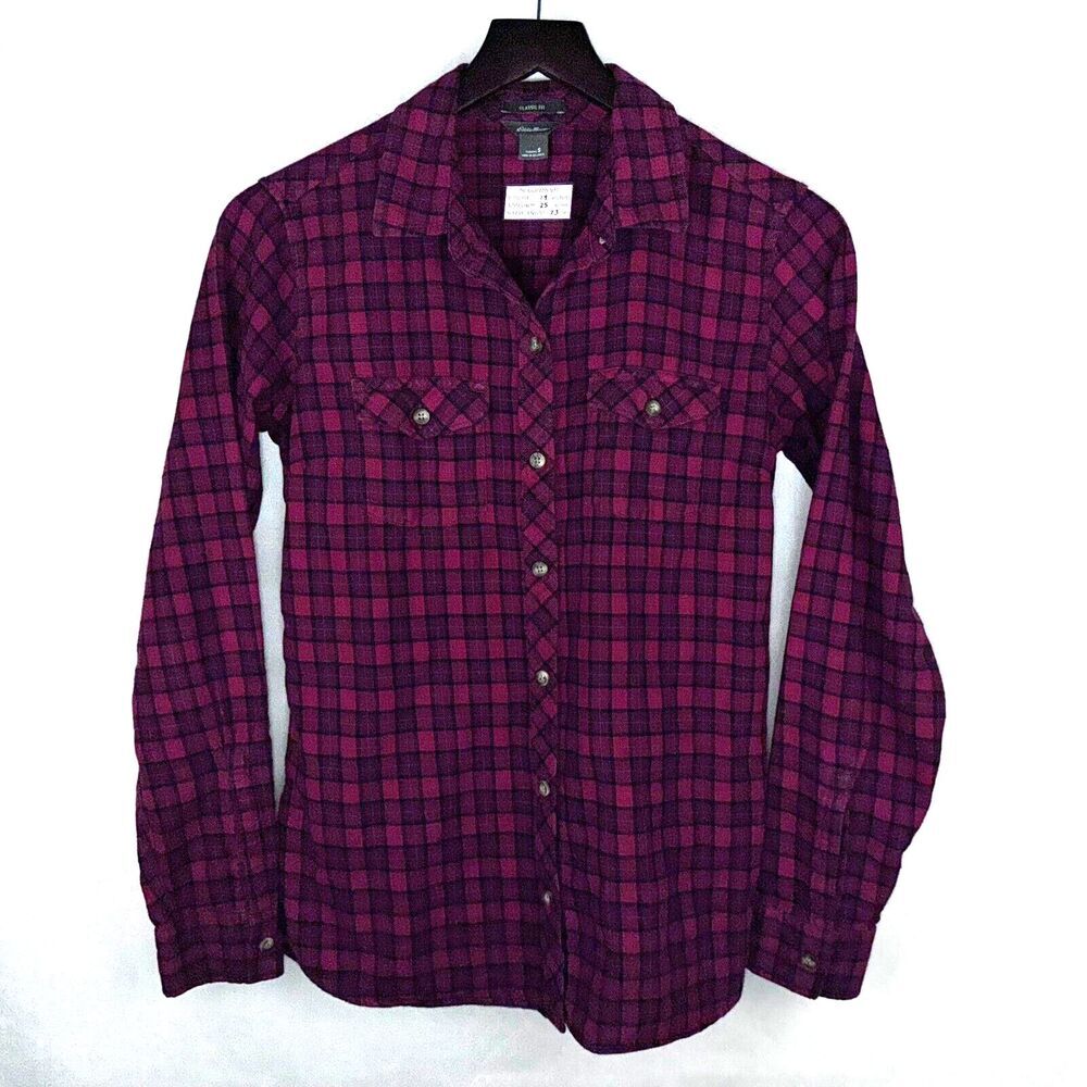 A long-sleeve button-up plaid shirt in dark magenta and black, hanging on a black hanger against a white background.