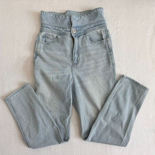 Light wash blue denim jeans laid flat on a light beige textured background.