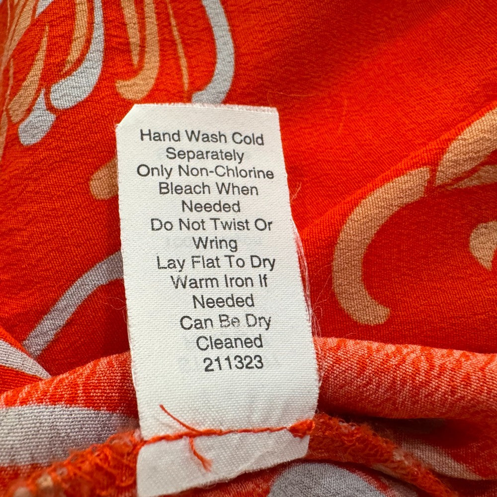 Clothing tag with washing instructions of an orange Cabi top 