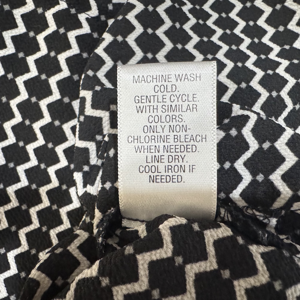 Clothing care tag view on Candies top displaying washing instructions on a black and white patterned background