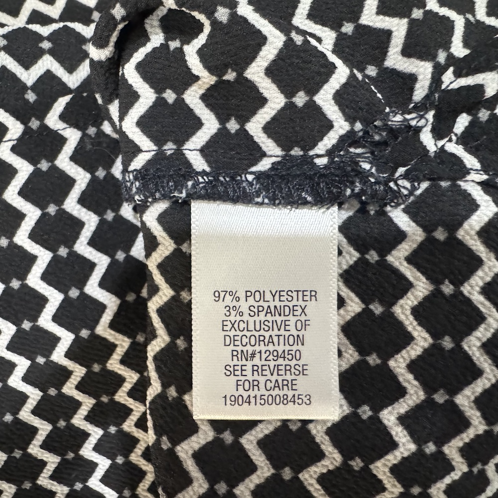 Clothing material tag view on Candies top black and white pattern and a label displaying fabric composition details.