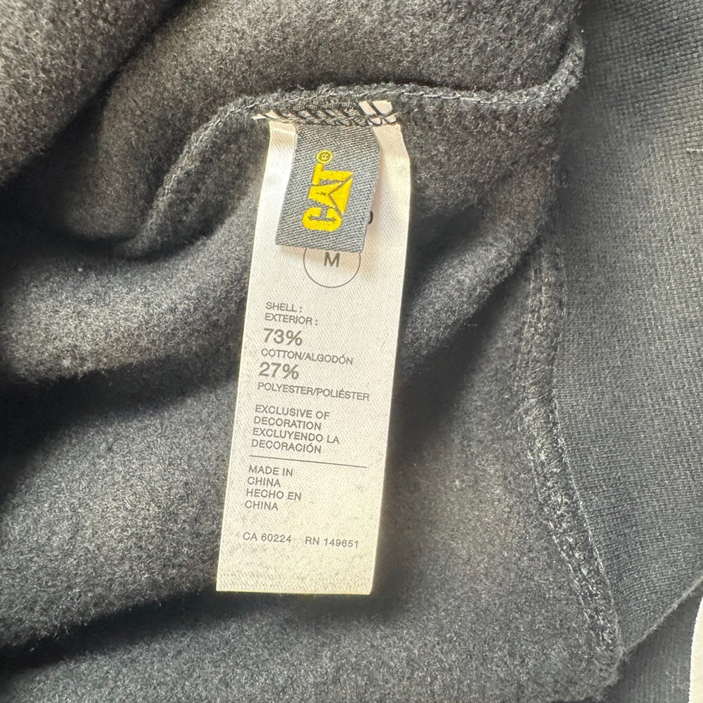 Close-up of a clothing tag on CAT black hoodie fabric size m