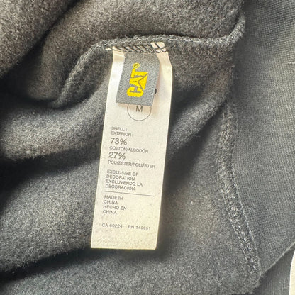 Close-up of a clothing tag on CAT black hoodie fabric size m