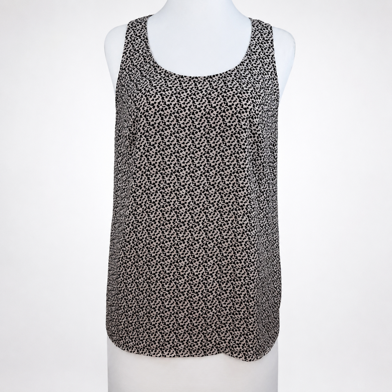A sleeveless scoop-neck top with an all-over small black and white floral or ditsy print, displayed on a white mannequin torso against a light gray background.