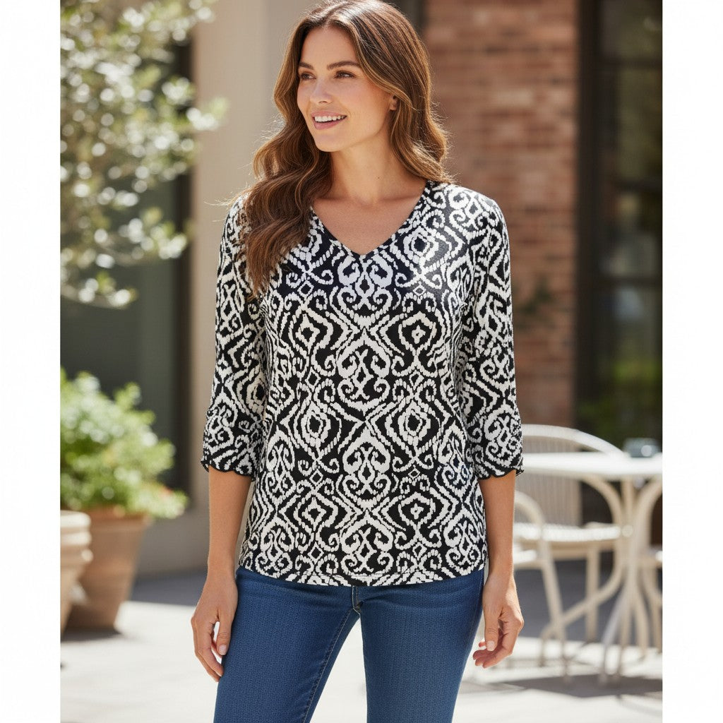 Chico's black and white geometric print V-neck top in Size 1 with 3/4 flared sleeves and stretch fabric in excellent used condition.