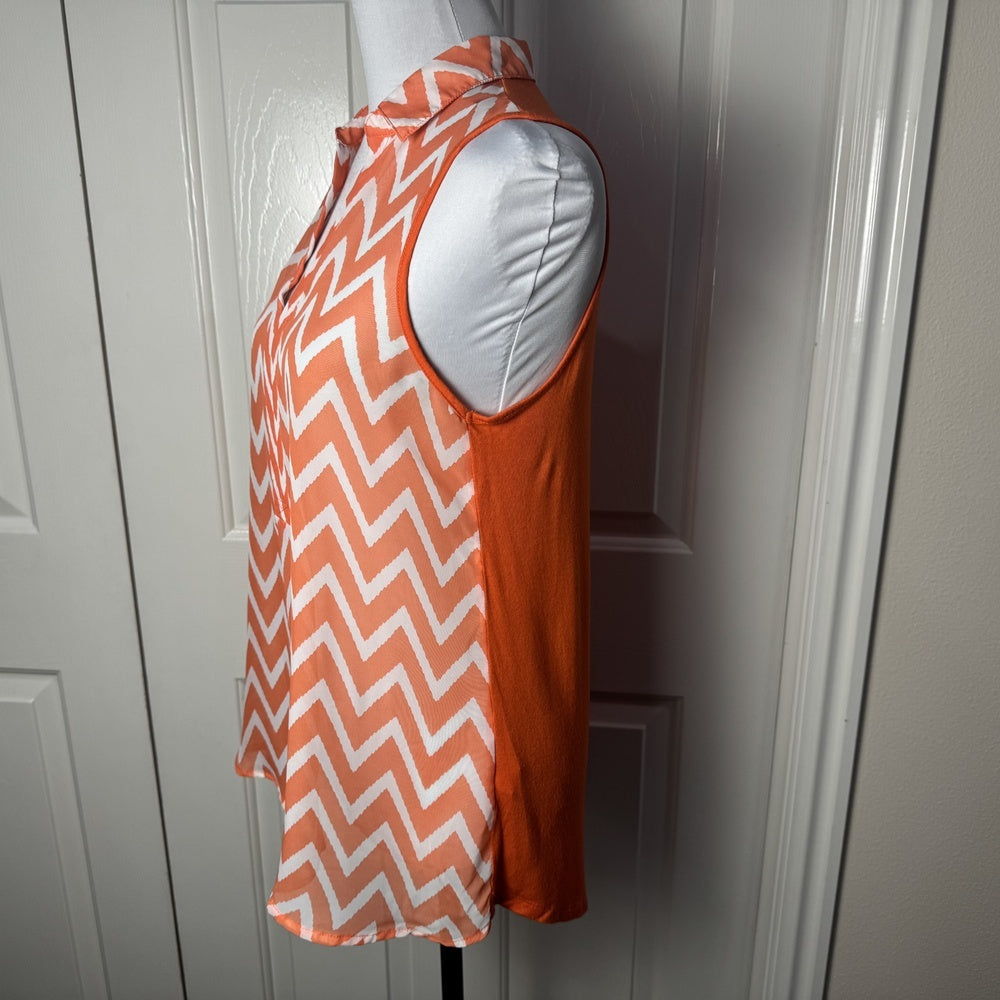 Side view on Femme by Tresics orange and white chevron patterned sleeveless top on a mannequin against a white door.