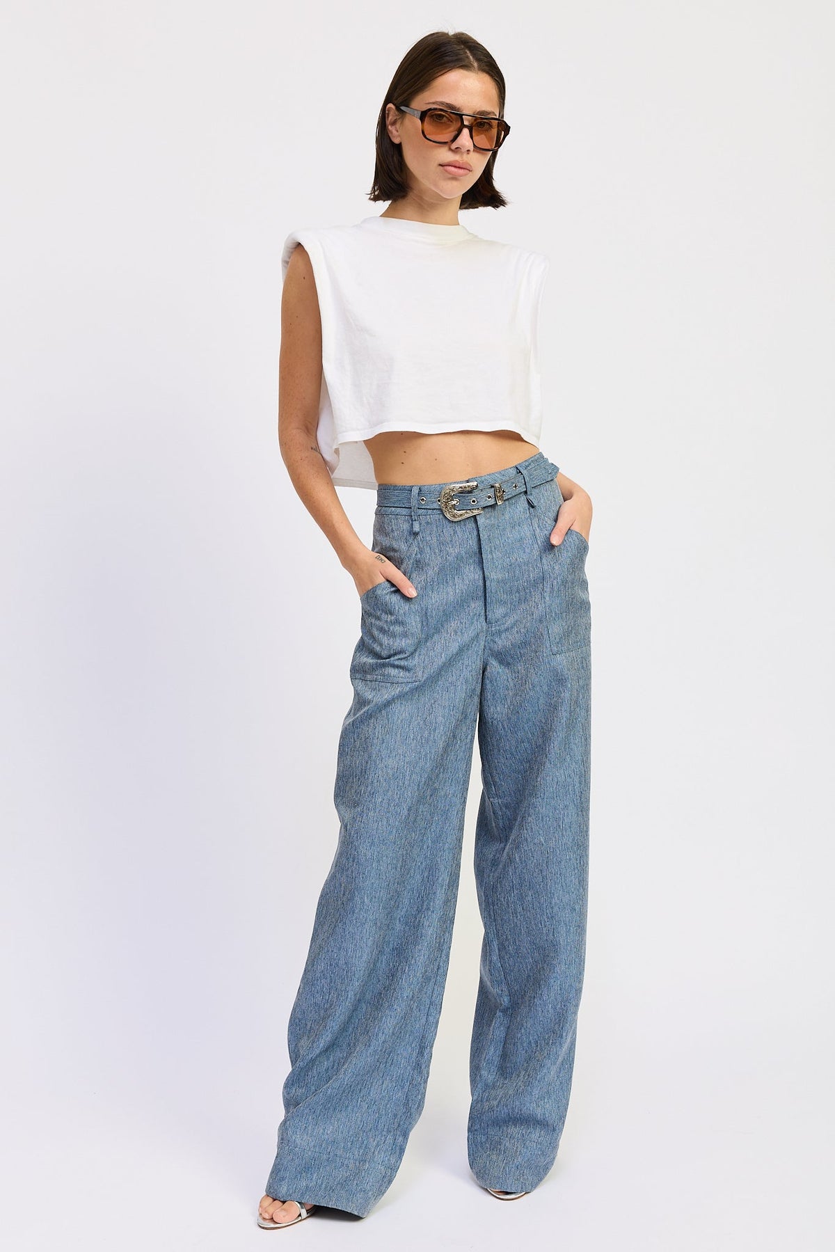 Model wearing Emory Park Jovie denim blue wide-leg trousers with matching belt, styled with a sleeveless white crop top.