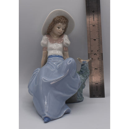 Height view of Lladro porcelain figurine of a woman with a long skirt and hat next to a ruler for scale