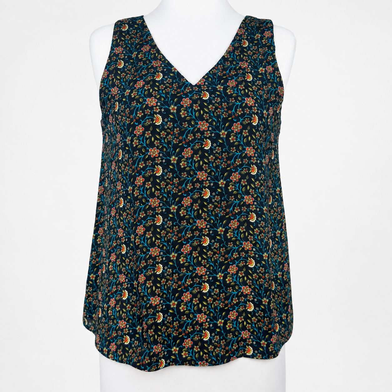 A sleeveless V-neck top with a dense floral and paisley print, displayed on a white mannequin torso against a plain white background.