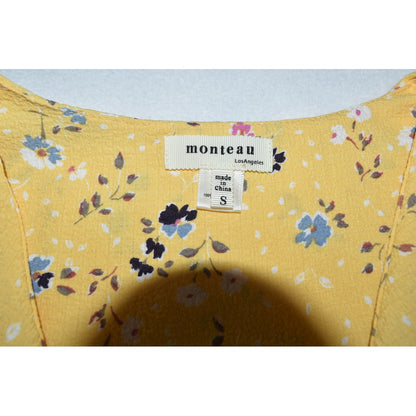 Clothing tag view on Monteau crop top yellow fabric with floral pattern on a light background
