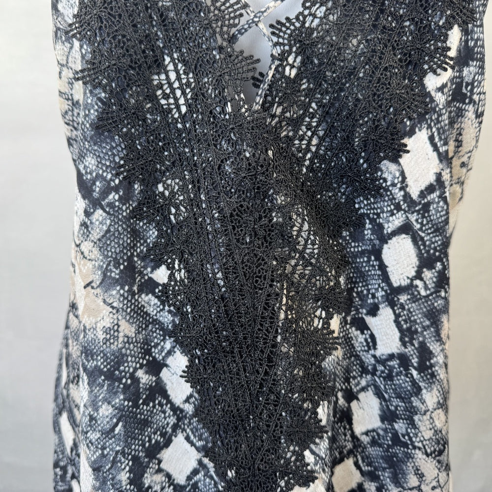 Front lower detail on Wayf camisole black lace garment with a patterned background