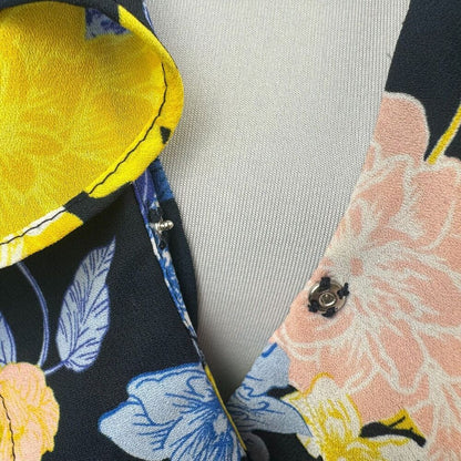 Blusa cruzada Banana Republic, talla S, negra con diseño floral y volantes, manga corta.