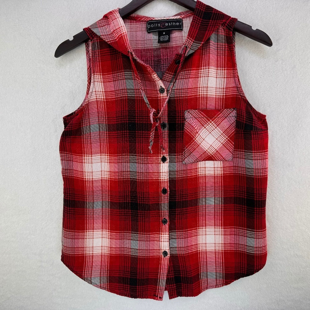 A sleeveless red and black plaid flannel shirt vest with a tie collar and chest pocket, hanging on a black hanger against a textured white wall.