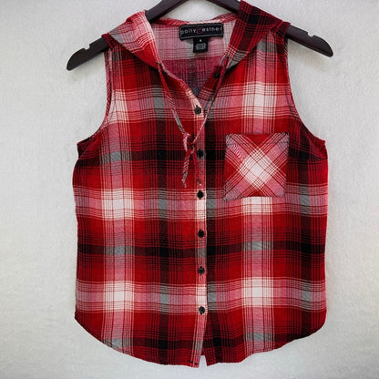A sleeveless red and black plaid flannel shirt vest with a tie collar and chest pocket, hanging on a black hanger against a textured white wall.