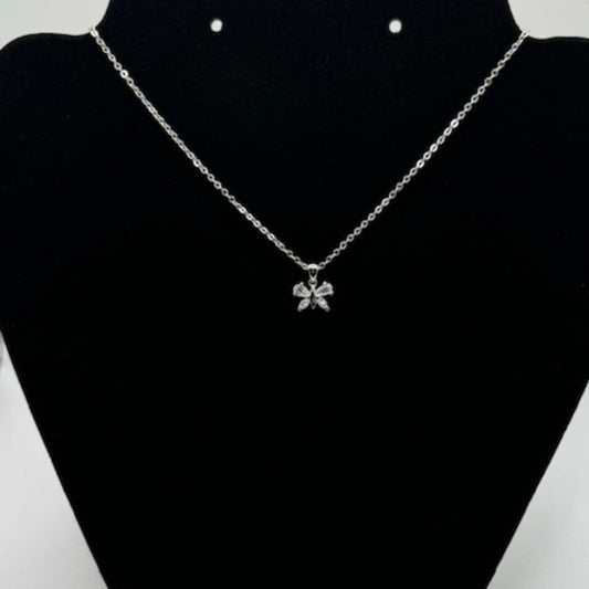 A silver chain necklace with a small bow-shaped pendant set with clear stones, displayed on a black jewelry bust.