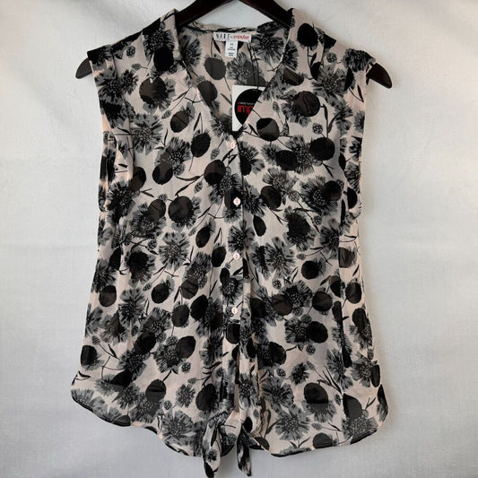 A sleeveless button-front blouse with a black floral and botanical print on a light beige background, hanging on a black hanger against a white fabric backdrop.