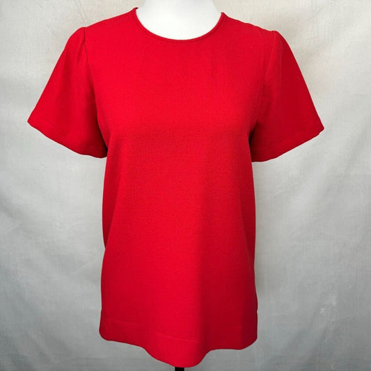 A bright red short-sleeve crewneck top displayed on a white mannequin torso against a light gray fabric backdrop.