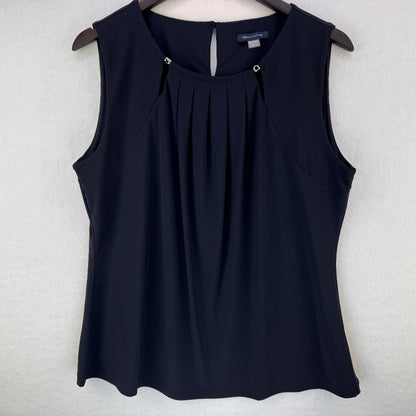 A sleeveless black top with a pleated front and keyhole back detail, hanging on a wooden hanger against a light gray textured wall.
