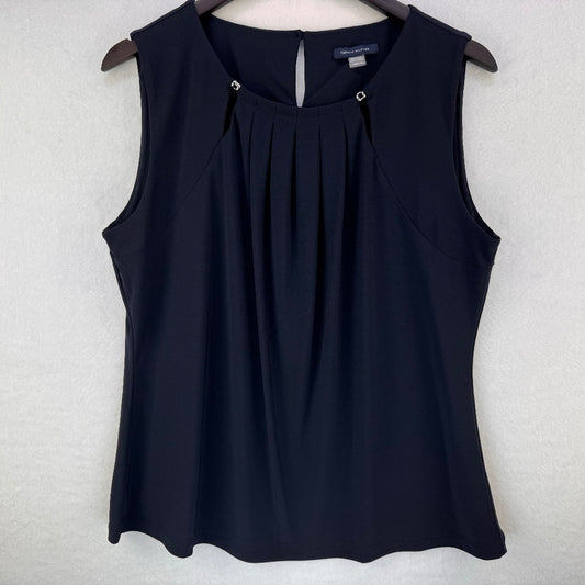 A sleeveless black top with a pleated front and keyhole back detail, hanging on a wooden hanger against a light gray textured wall.
