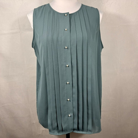 A sleeveless, scoop-neck blouse in a muted teal-green color, featuring vertical pleats and a front button closure with pearl-like buttons, displayed on a white mannequin torso against a neutral beige fabric backdrop.