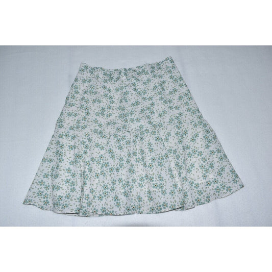 A white A-line skirt with a green floral pattern, laid flat against a light gray background.