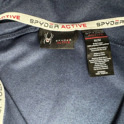 Close-up of a Spyder Active garment interior showing the Spyder logo on the neck label and care tag, with blue-gray fabric and a white branded elastic band.
