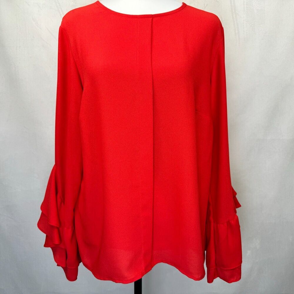 A bright red long-sleeve blouse displayed on a mannequin torso against a light gray fabric backdrop.