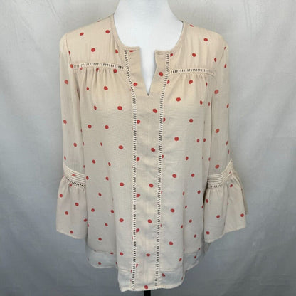 A cream-colored blouse with red polka dots and decorative stitching, displayed on a white mannequin torso against a gray fabric backdrop.