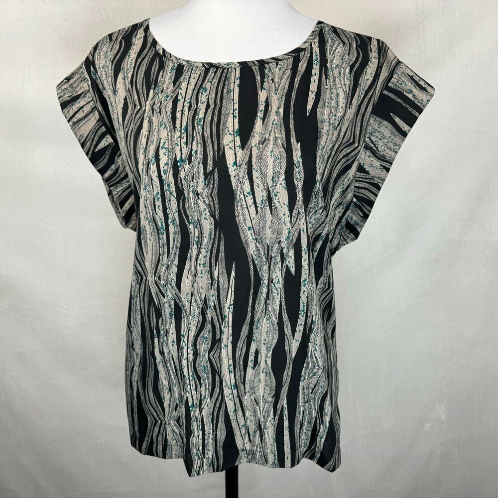 A short-sleeve top with an abstract wavy black, gray, and white pattern, displayed on a white mannequin torso against a light gray fabric backdrop.