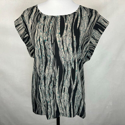 A short-sleeve top with an abstract wavy black, gray, and white pattern, displayed on a white mannequin torso against a light gray fabric backdrop.