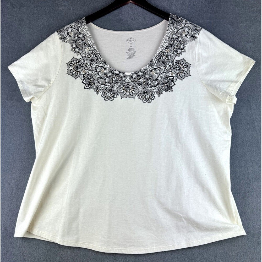 An off-white short-sleeve top with a black floral lace collar, hanging on a black hanger against a dark gray background.