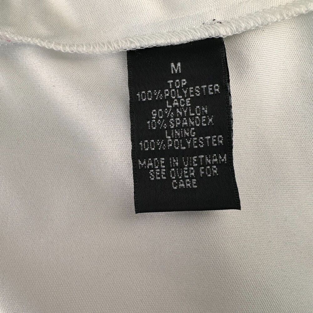 Close-up of a black garment care label sewn onto white fabric, showing text including size M and material details.