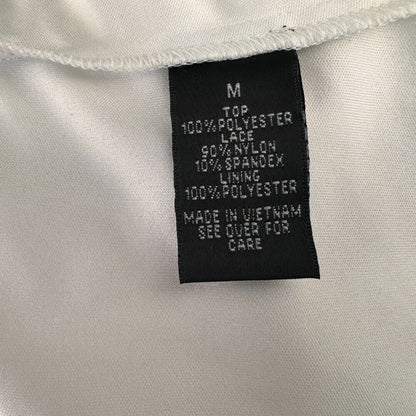 Close-up of a black garment care label sewn onto white fabric, showing text including size M and material details.