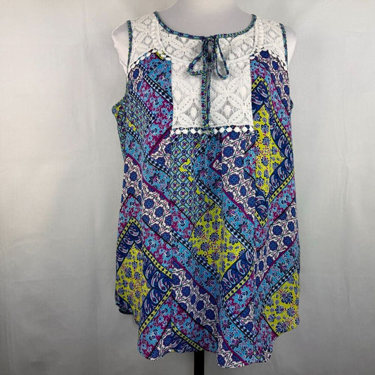 A sleeveless bohemian-style top with a white lace yoke and necktie, featuring a multicolor patchwork print of blue, purple, yellow, and pink geometric patterns, displayed on a mannequin against a light gray background.