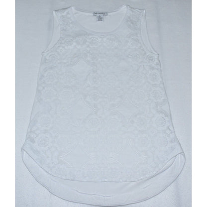 A white sleeveless top with an intricate floral lace overlay, laid flat on a white textured fabric background.