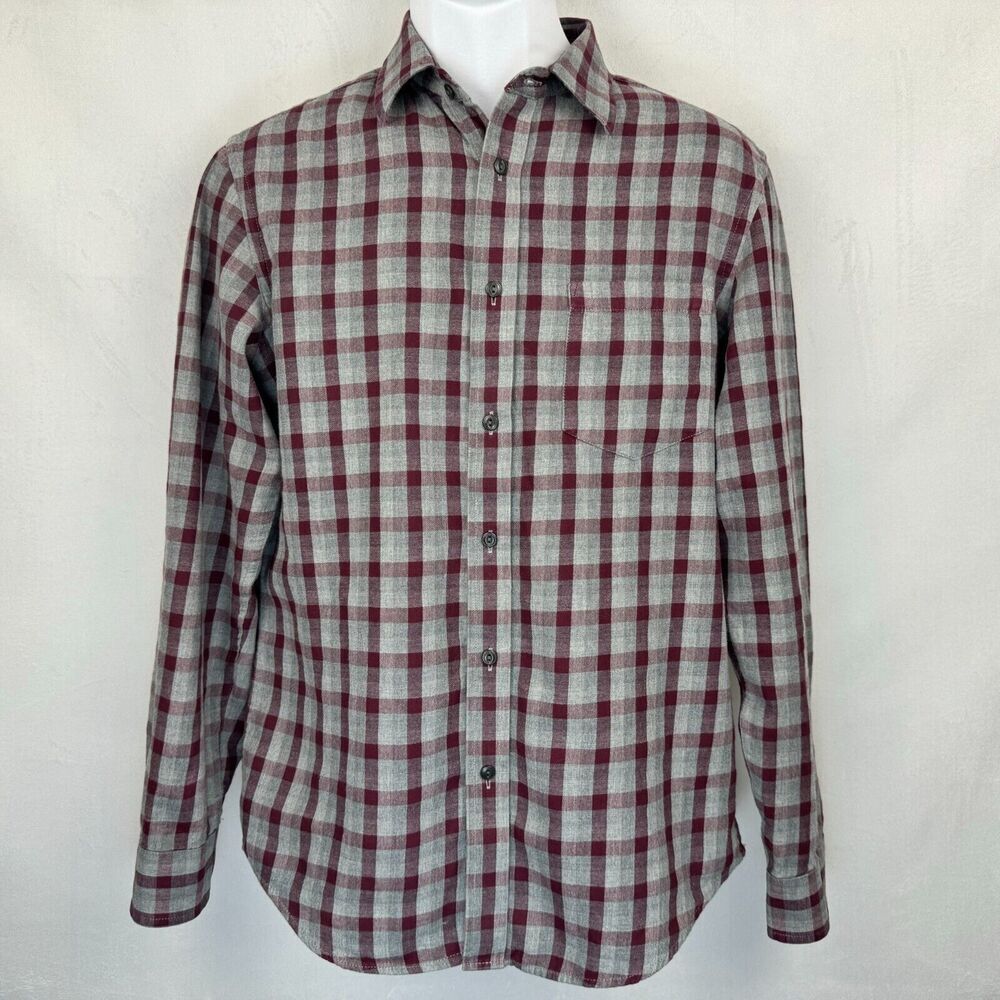 A long-sleeve button-up plaid shirt in a gray and burgundy checkered pattern, displayed on a white mannequin torso against a light gray textured background.