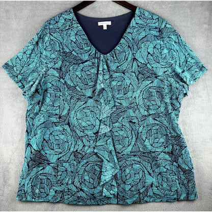 A short-sleeve V-neck blouse with a teal and navy blue abstract floral pattern, hanging on a dark hanger against a gray textured background.
