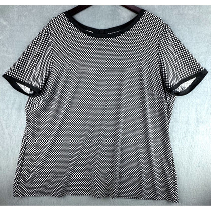A black and white micro-dot patterned short-sleeve t-shirt with solid black trim on the crew neck and sleeve cuffs, displayed flat on a hanger against a light gray textured background.