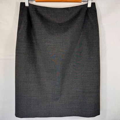 A dark charcoal gray textured pencil skirt hanging from a wooden hanger with white clips against a white fabric backdrop.