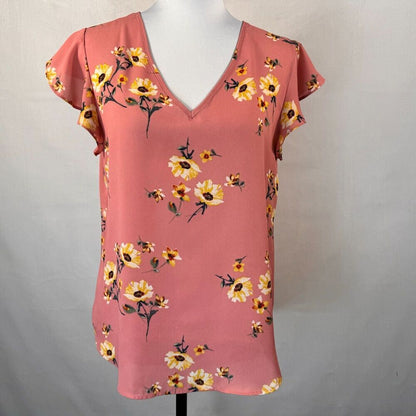 A pink short-sleeve V-neck blouse with a yellow and white floral print, displayed on a white mannequin torso against a light gray background.