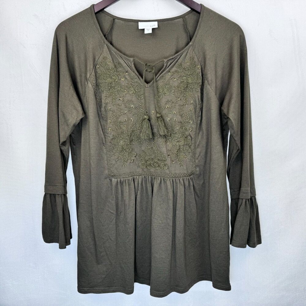 An olive green long-sleeve tunic top with a lace-up neckline and embroidered chest detailing, hanging on a dark hanger against a light gray background.