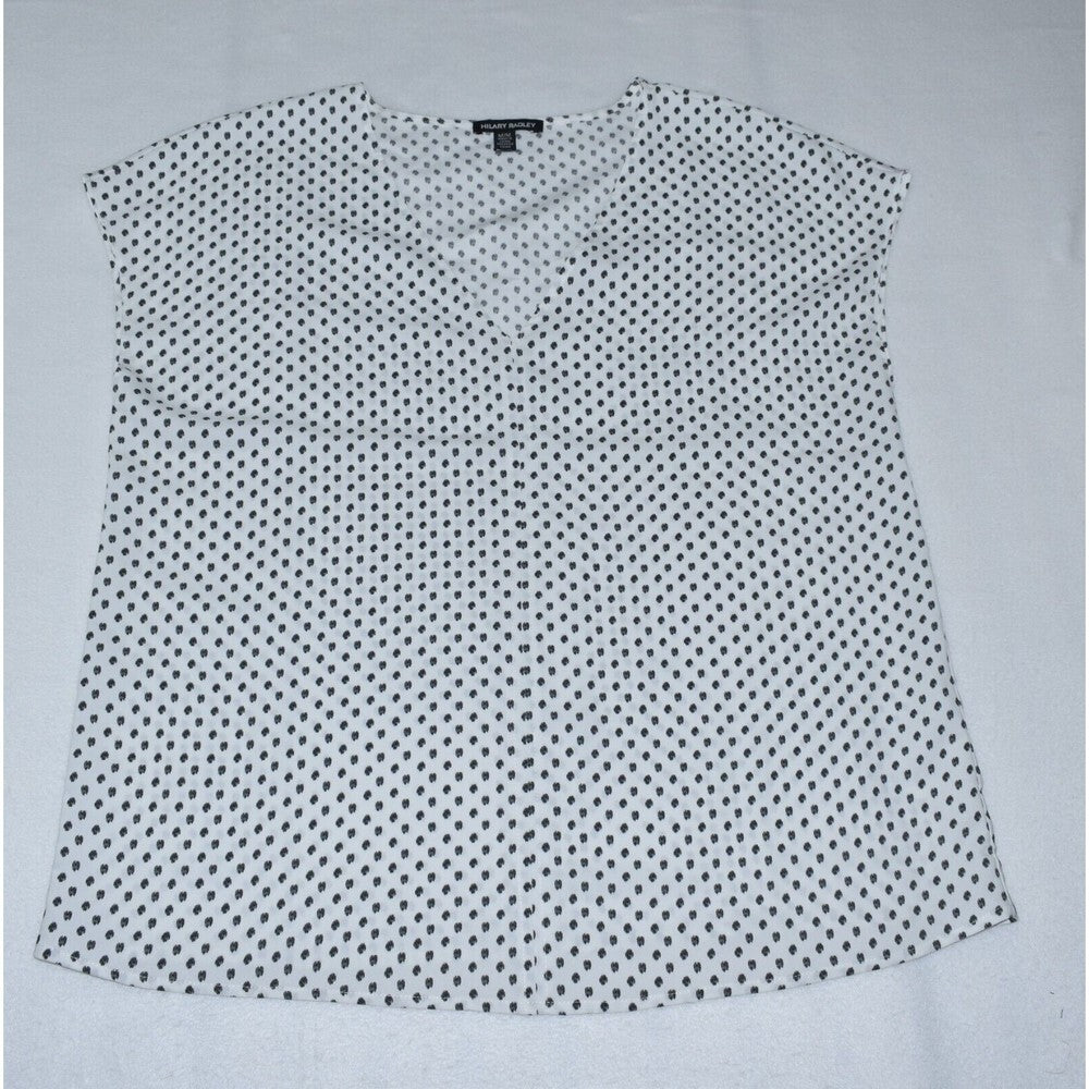 A sleeveless white blouse with a small black polka dot pattern, laid flat on a light gray background.