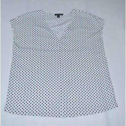 A sleeveless white blouse with a small black polka dot pattern, laid flat on a light gray background.